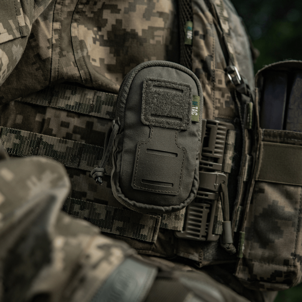 Sotilas, jolla M-Tac PC Utility Pouch Elite kiinnitetty MOLLE-järjestelmään, monikäyttöinen Cordura-laukku pikkutavaroille taktisissa oloissa.