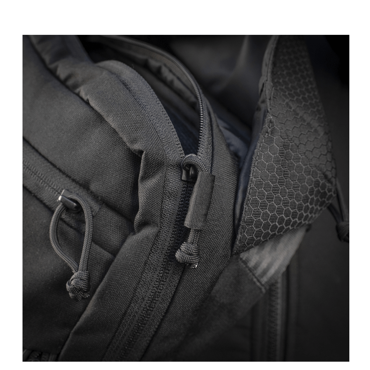 Yksityiskohta M-Tac Magnet XL Taske Elite Hexistä, FidLock-lukitusjärjestelmä ja olkahihna; näyttää vahvan kankaan ja vetoketjusuunnittelun.