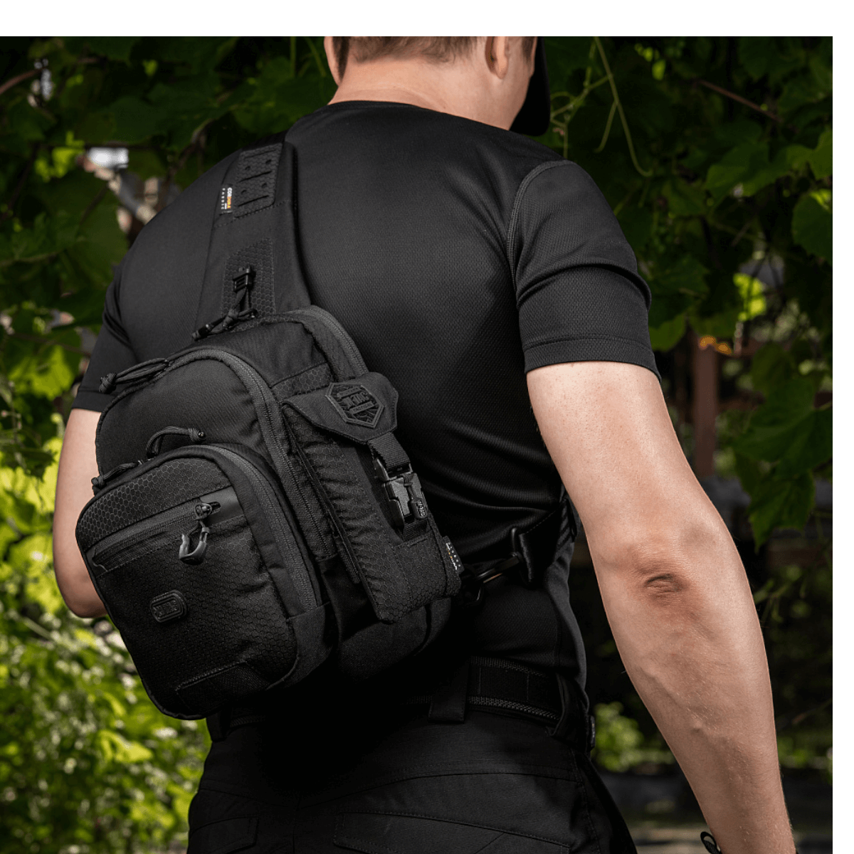 Mies kantaa mustaa M-Tac Smartphone Lomme Elite Large Hex -taskua, valmistettu CORDURA HEX -materiaalista, sopii puhelimille jopa 6,5 tuumaa.