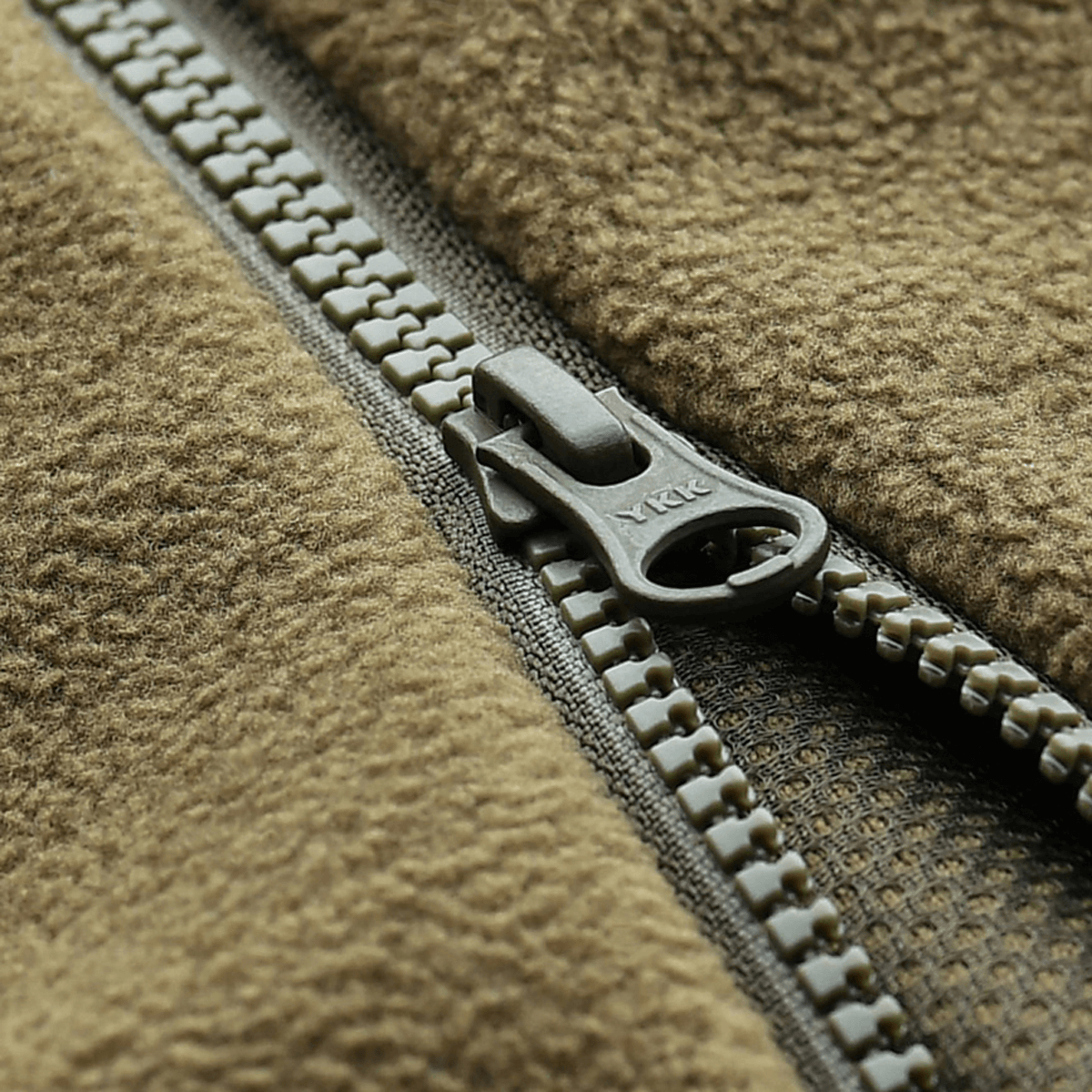 Lähikuva vetoketjusta M-Tac Lite Microfleece Hættetrøje -hupparissa, korostaa joustavaa mikrofleeceä ja mesh-strukturia.