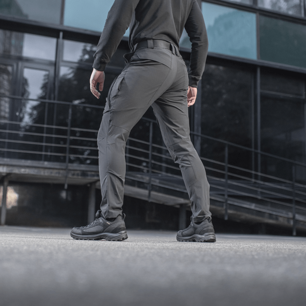 Henkilö pukeutuneena M-Tac Rubicon Flex -housuihin, sopivat harjoitteluun ja työhön, modernissa kaupunkiympäristössä. Mukava 4-Way Stretch -kangas.