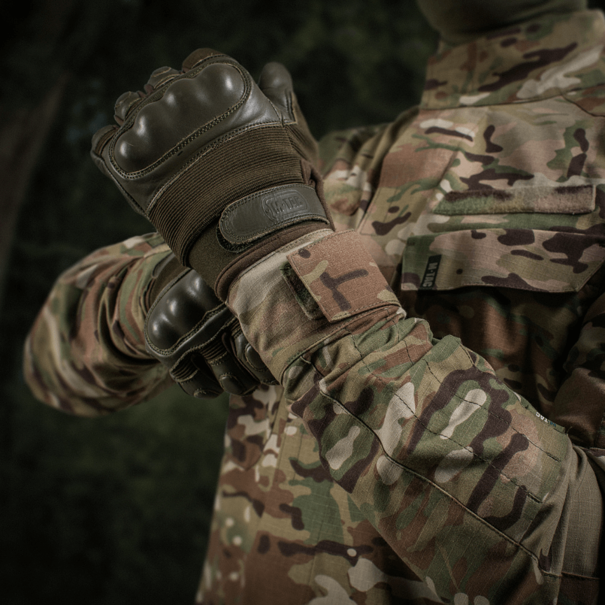 M-Tac Jakke Sturm NYCO Extreme Multicam-kuosissa, sotilastakki kestävästä nylon-puuvillakankaasta, esitetty luonnon maisemassa.