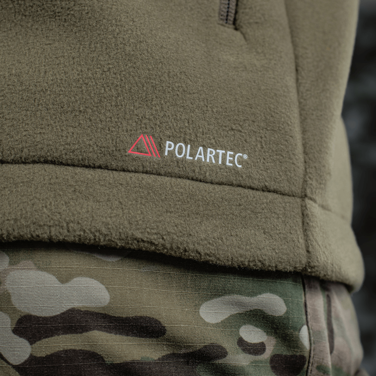 M-Tac Combat Fleece Polartec -takki Polartec®-logolla, lähikuva takista ja maastohousuista taktiseen ilmeeseen.
