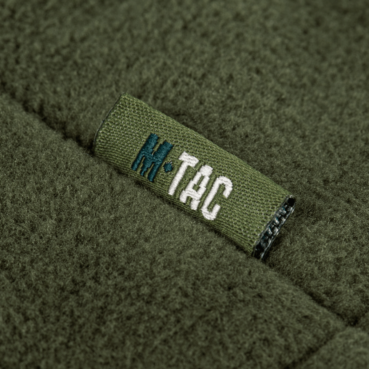 M-Tac Combat Fleece Polartec -takin kankaan yksityiskohta, logo vihreässä fleecessä.