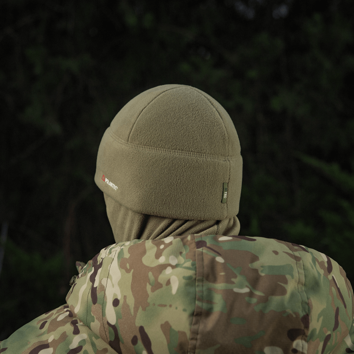 Henkilö, jolla on M-Tac Fleece Polartec Watch Cap ja naamiointikuosinen takki metsässä