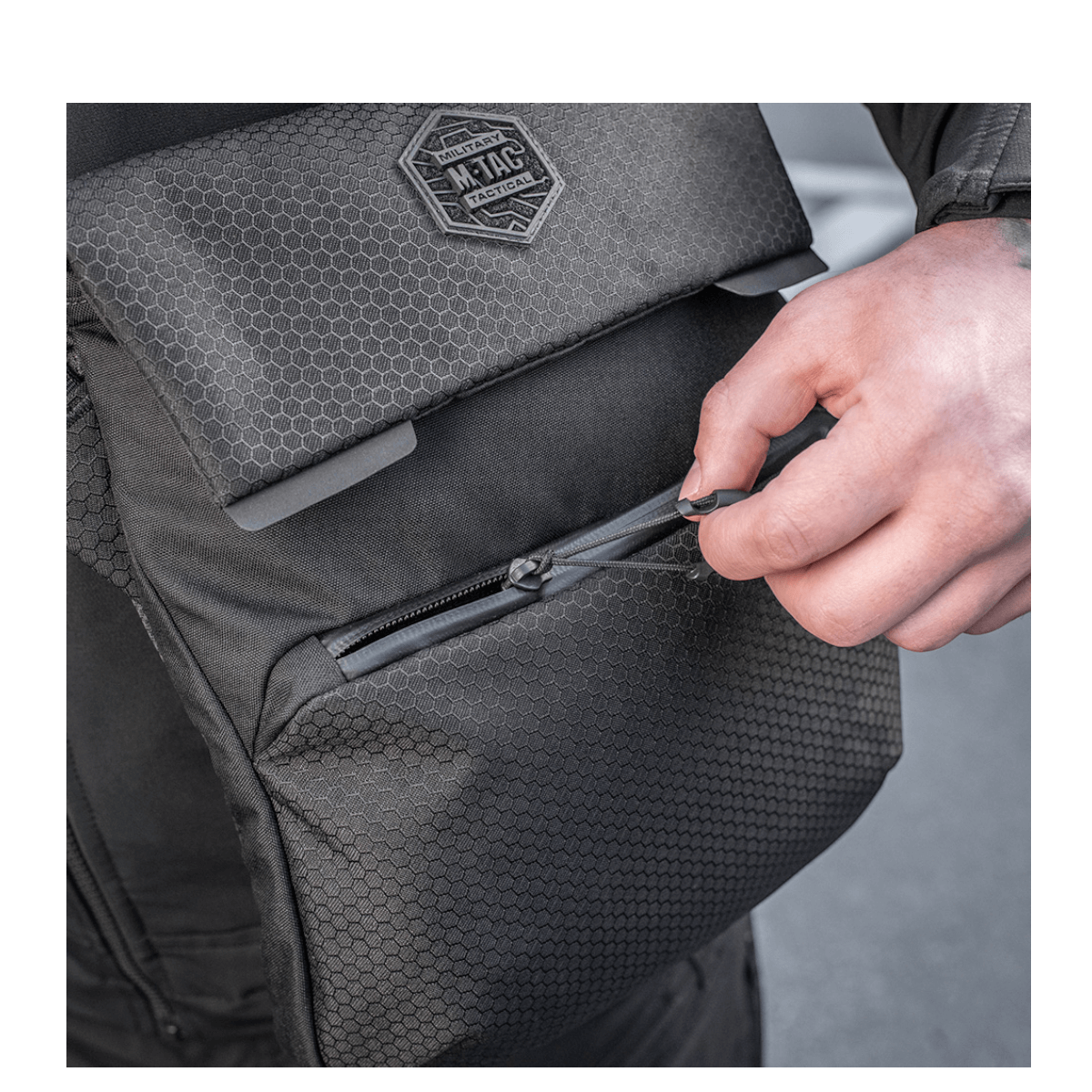 M-Tac Konvert Taske Elite Cordura Hex 1000D:llä, säädettävä olkahihna ja magnetisk lukko, lähikuva lynlås-detaljista.