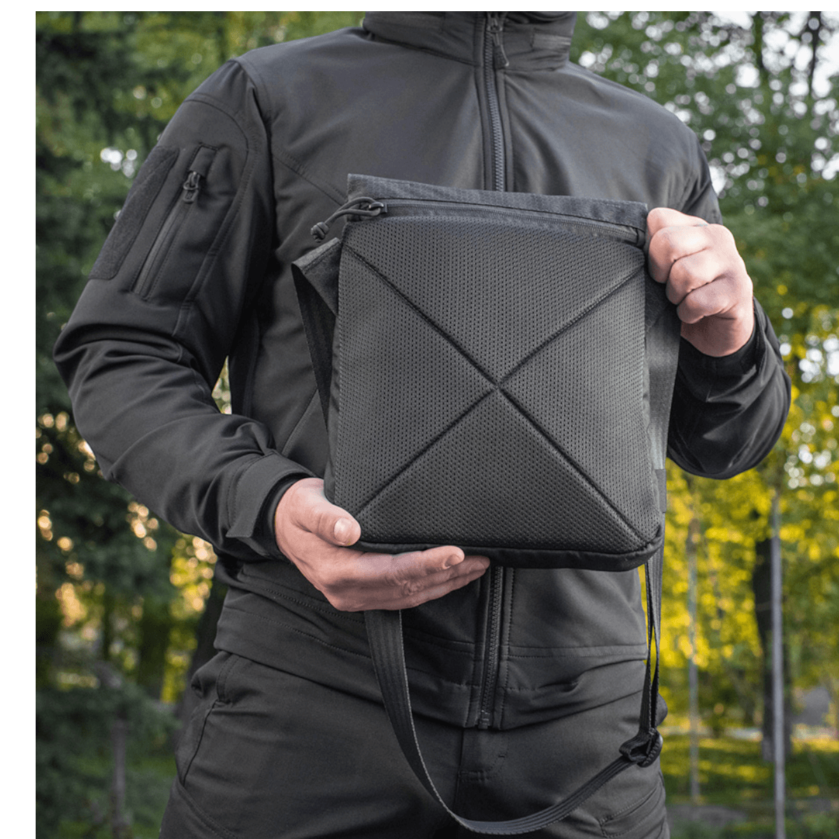 Mies pitää M-Tac Konvert Taske Eliteä mustana, valmistettu Cordura-materiaalista, säädettävä olkahihna ja tablet-design.