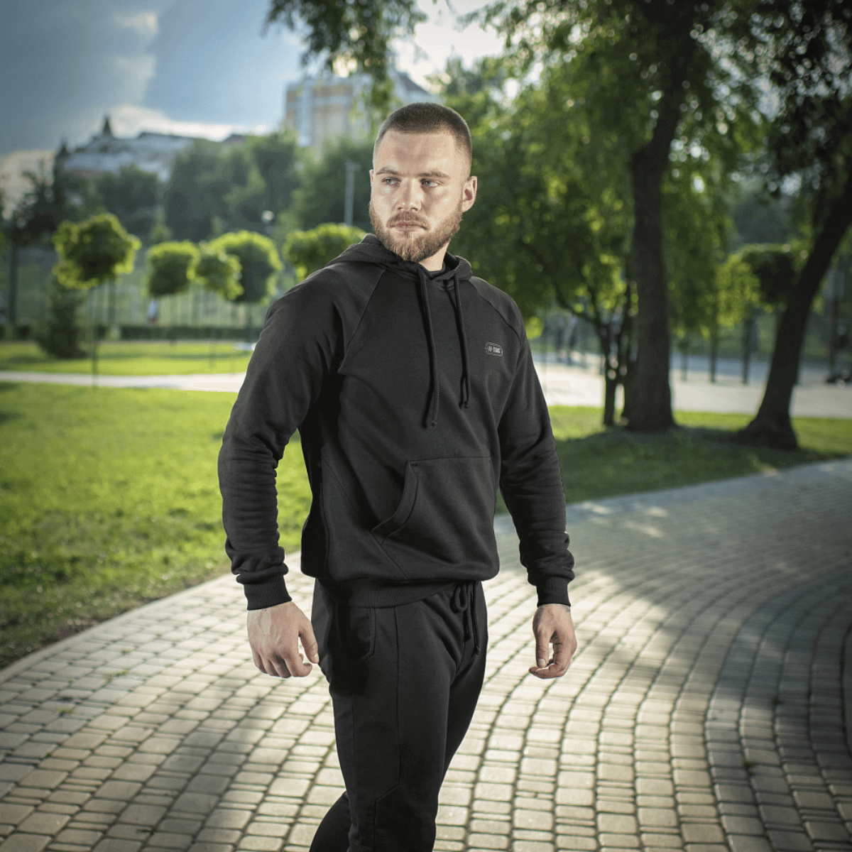 Mies M-Tac Cotton Raglan -hupparissa puistossa, korostaa mukavuutta ja tyyliä arkeen ja aktiiviseen käyttöön.