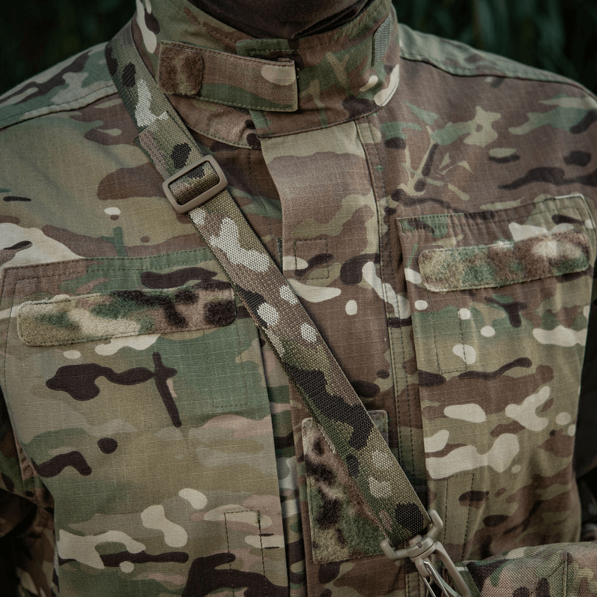Maastokuvioitu uniformu metsäkuvioidulla hihnalla taktista tehtävää varten luonnossa.