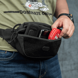 Henkilö käyttää M-Tac Tactical Waist Bag Gen.II Elitea säilytykseen; näyttää kestävyyden ja toimivuuden mustassa designissa, sopii päivittäisiin aktiviteetteihin.