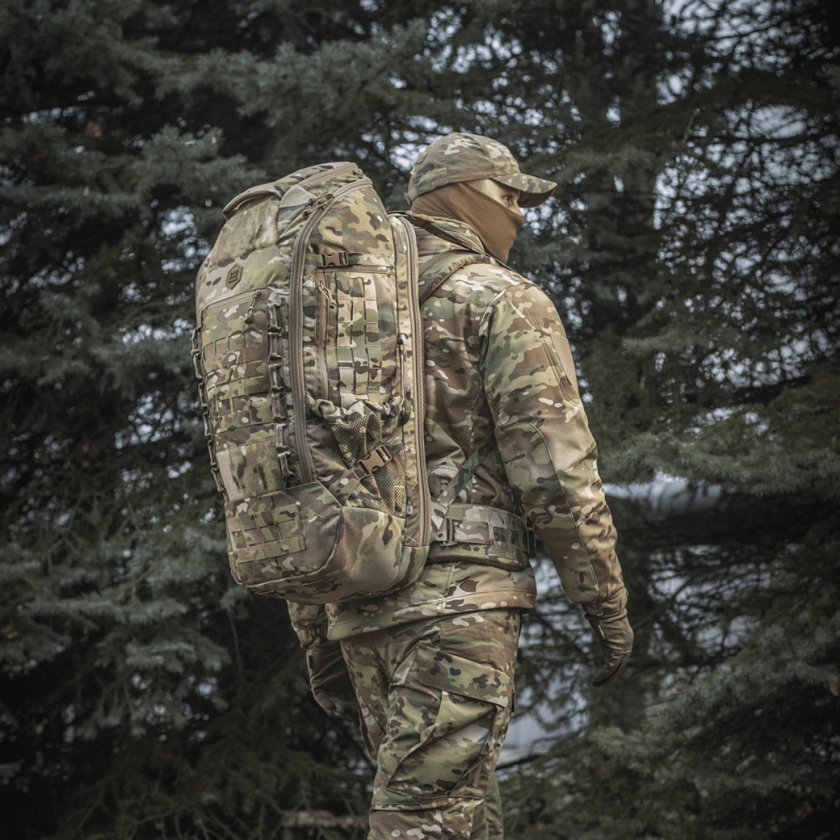 M-Tac Rygsæk Large Gen.III Elite taktiseen käyttöön, henkilö kantaa sitä camouflagessa varustuksessa ulkona metsässä.