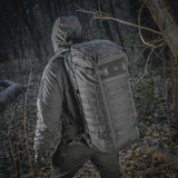 Henkilö kantaa M-Tac Rygsæk Gen.II Elite Largea metsäympäristössä.