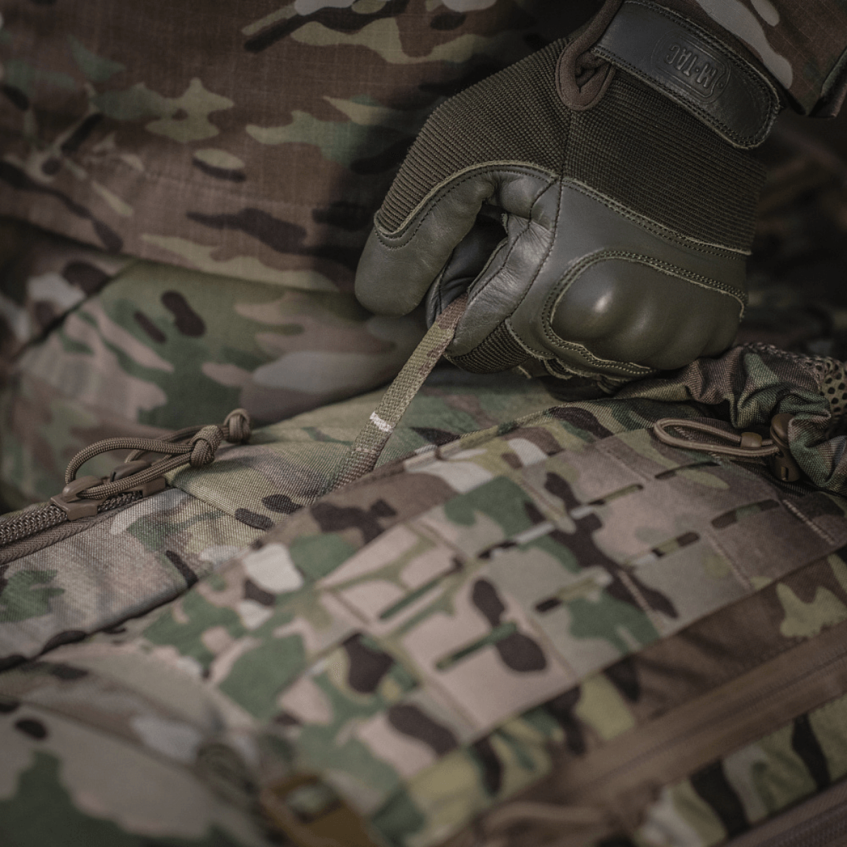 Yksityiskohtainen kuva M-Tac Large Gen.IV Elite -repusta käytössä, näyttää kestävän Cordura-materiaalin maastokuvioinnilla.