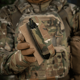 Sotilas pitää M-Tac Tourniquet Pouch Elastisk VELCRO Gen.II:tä, Cordura 500D, kiinnitettynä VELCRO-paneeliin plate carrierin läpän alla