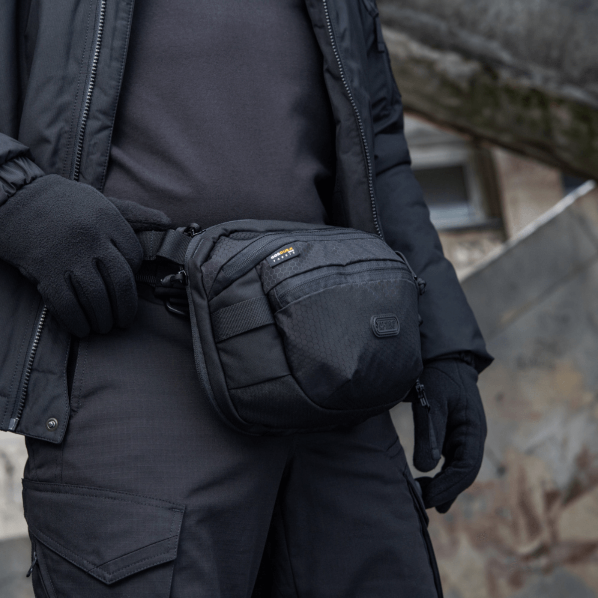 M-Tac Sphaera Hex Hardsling Bag käytössä olka- tai vyölaukkuna, kompakti muotoilu, piilotettu aseenkotelo, Cordura/Hex-polyesteristä.