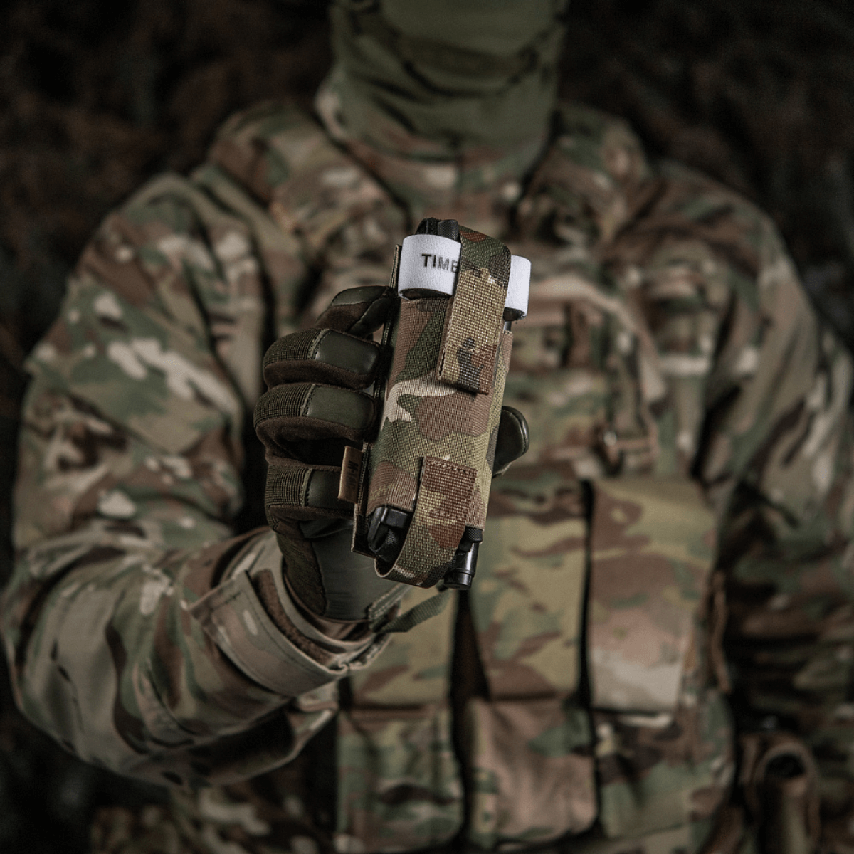 Sotilas maastopuvussa pitää M-Tac Elastinen turnikekotelo Molle Gen.III edessään, valmiina nopeaan käyttöön.