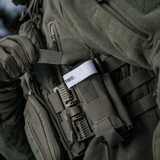 M-Tac Elastinen turnikekotelo Molle Gen.III kiinnitetty taktiseen liiviin, näyttää käytännöllistä käyttöä ja helpon pääsyn tourniquettiin.