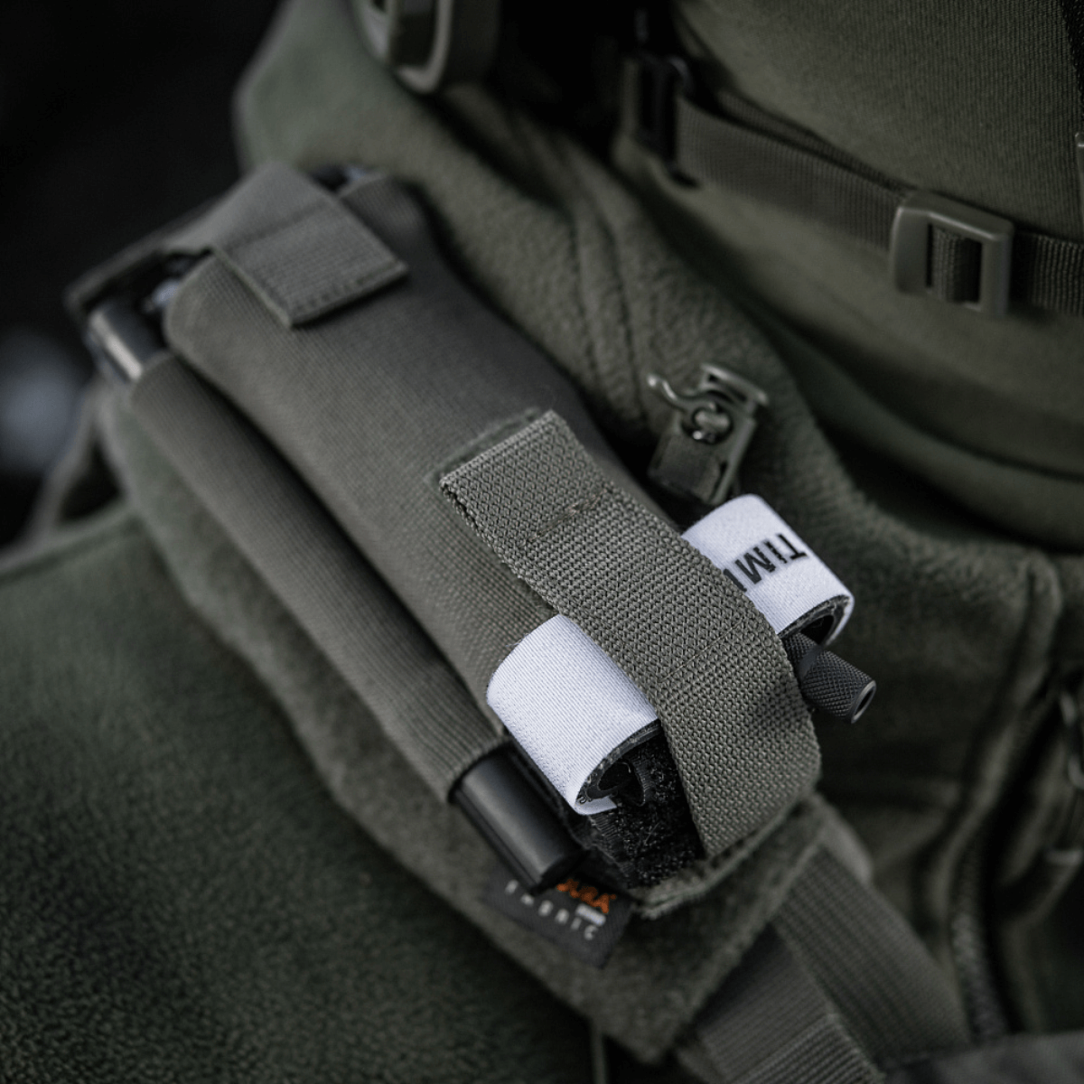 M-Tac Elastinen turnikekotelo Molle Gen.III kiinnitettynä takkiin, Cordura Squadron -materiaalista, leveällä elastilla C-A-T tourniquetille.
