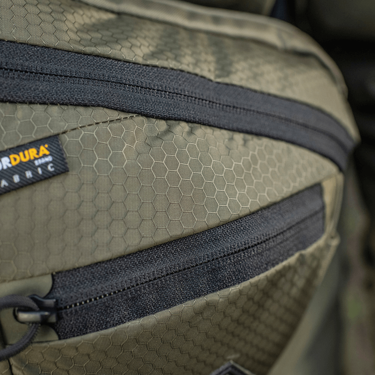 M-Tac Sphaera Hex Hardsling Gen.II Elite Cordura-materiaalilla, hex-kuvio ja vetoketjun yksityiskohta; korostaa toiminnallista laukunsuunnittelua.