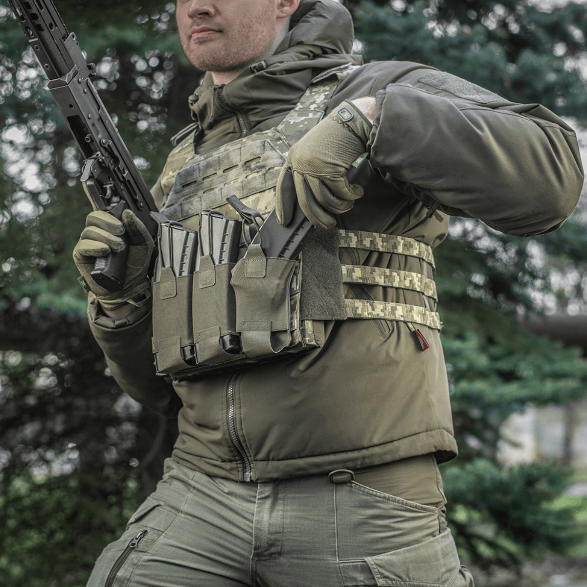 M‑Tac Elastinen Triple Magazine Pouch Elite kiinnitetty taktiseen liiviin kolmella lipalla, suunniteltu nopeaan käyttöön ja turvalliseen säilytykseen