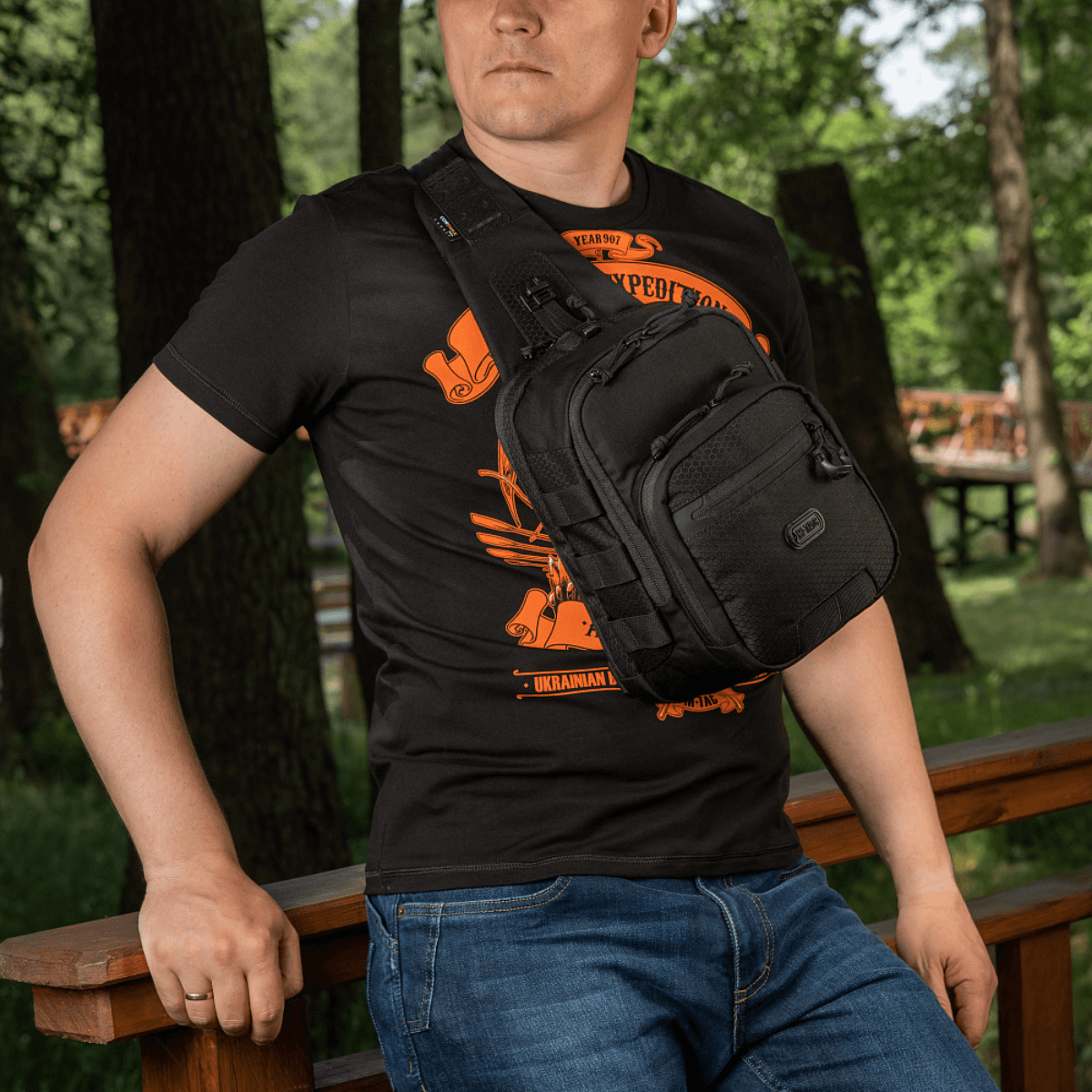 Mies kantaa M‑Tac Cross Bag Elite Hex -sling-laukkua, Cordura 500, sopii päivittäiskäyttöön ja taktiseen varustukseen