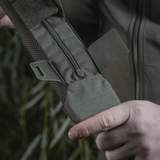 Henkilö pitelee M‑Tac olkahihnan pehmikettä 50 mm Elite robustista Cordura-materiaalista, vetoketjukiinnitys ja 3D-mesh-ventilaatio.