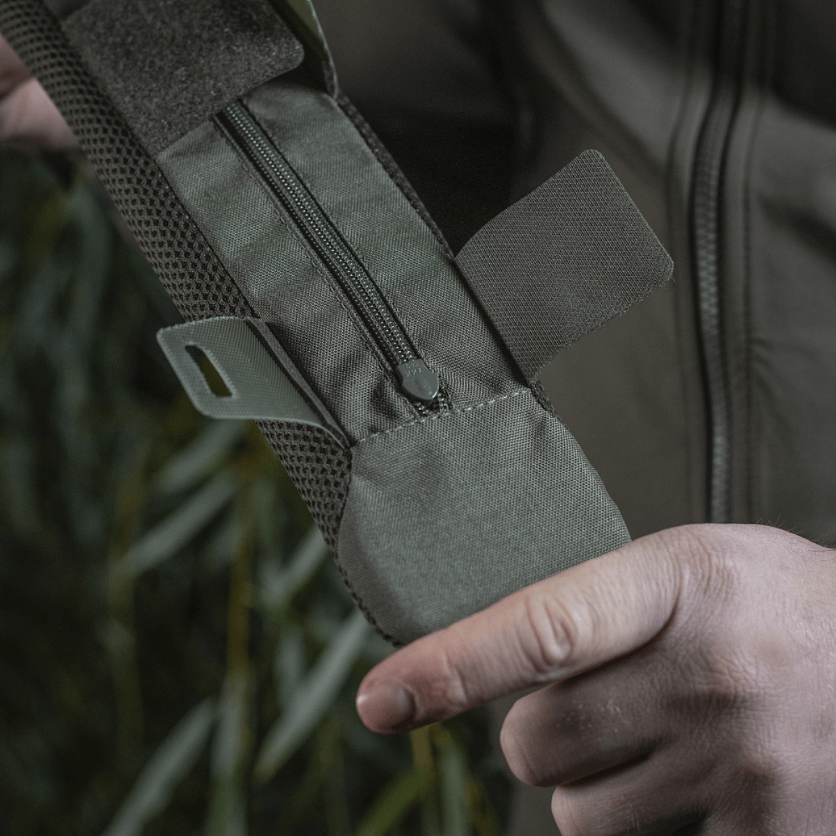 Henkilö pitelee M‑Tac olkahihnan pehmikettä 50 mm Elite robustista Cordura-materiaalista, vetoketjukiinnitys ja 3D-mesh-ventilaatio.