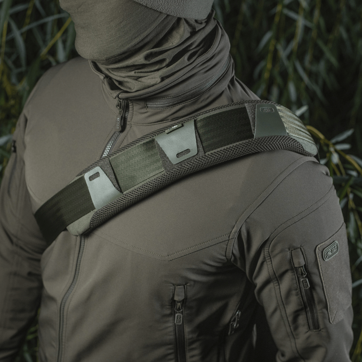 M‑Tac olkahihnan pehmike 50 mm Elite kiinnitettynä olkapäälle, 3D-mesh mukavuuteen ja Cordura kestävyyteen, käytössä taktisen takin kanssa.