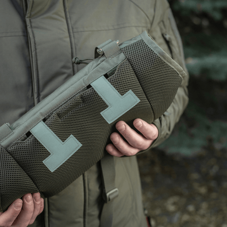 Henkilö pitää M-Tac Taktisk Håndvarmer Eliteä, valmistettu kestävästä Cordura 500D:stä, fleecevuori ja G-Loft-eristys kylmään säähän