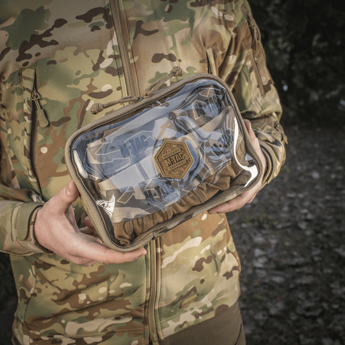 M-Tac Utility Organizer Slim Elite maastokuvioituna, henkilön pitämä, näyttää kestävän Cordura 500D:n ja PVC-kalvon nopeaan tunnistukseen.