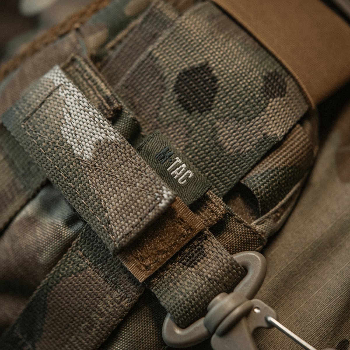 M-Tac karabiinihaka-lisävaruste kiinnitettynä MOLLE-järjestelmään, kevyt ja kompakti karabiinihaka säädettävällä Velcro-remmillä ja varma lukitus.