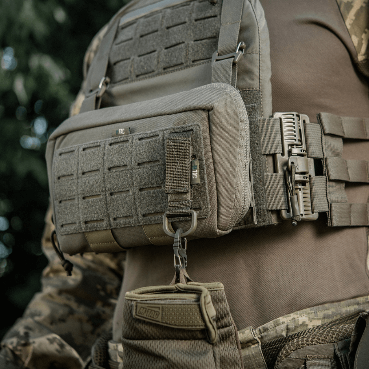 M-Tac-kiinnike D-renkaalla asennettuna taktiseen liiviin, MOLLE-järjestelmä ja Velcro-suljin.