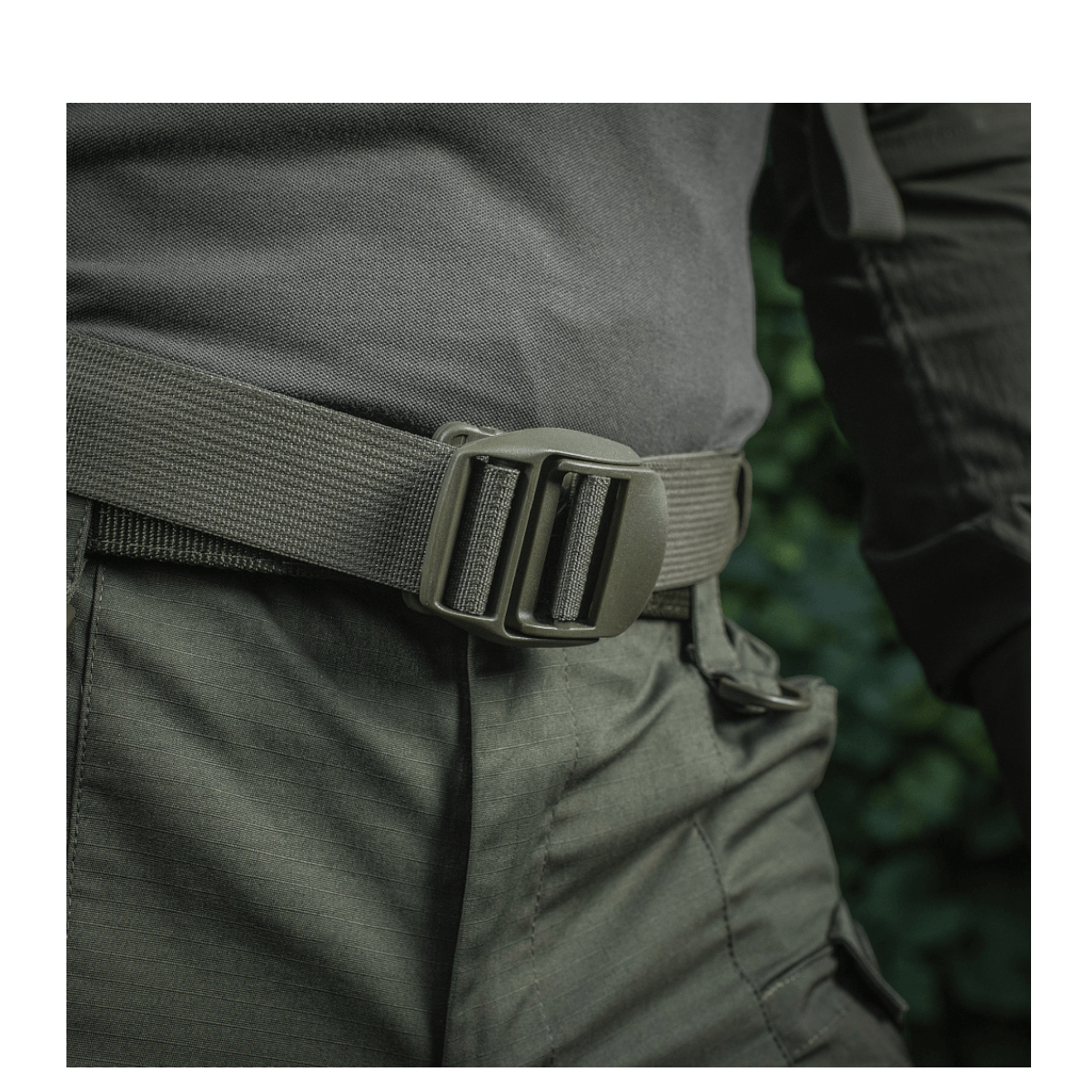 Mies pukeutuneena M-Tac Mission Rygsæk Elite Hex -reppuun Cordura-materiaalista ja MOLLE LASER CUT -järjestelmällä, lähellä vyötä.