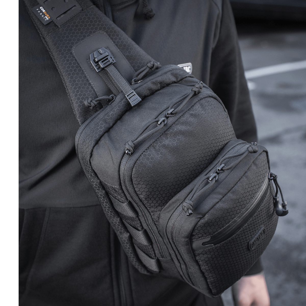 Mies kantaa M-Tac Cross Taske Slim Elite Hex -laukkua mustana olallaan.
