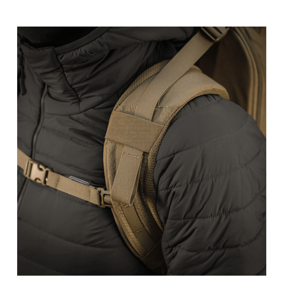 M-Tac reppu Large Elite Hex Gen. IV henkilöllä mustassa takissa, lähikuva ergonomisista olkahihnoista.
