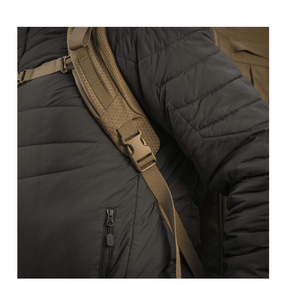 Henkilö mustassa takissa kantaa M-Tac reppu Large Elite Hex Gen. IV säädettävillä remmeillä ja ergonomisella muotoilulla.