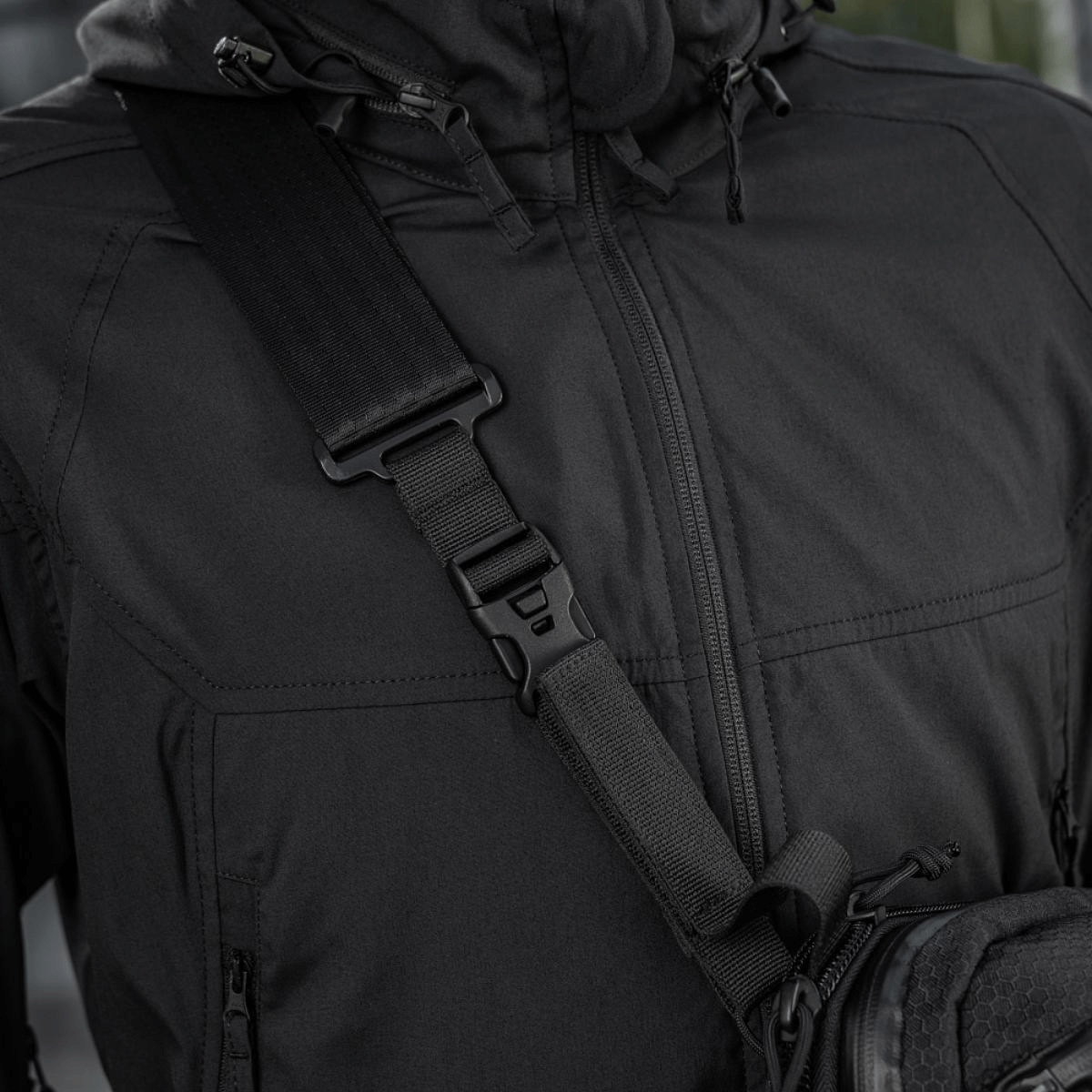 Lähikuva mustasta M-Tac Tablet Bag Laser Cut Hex -olkalaukusta henkilöllä, valmistettu kestävästä Cordura-materiaalista, säädettävä hihna.