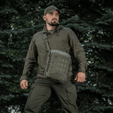 Henkilö M-Tac Tablet Bag Laser Cut Hex -laukulla metsämiljöössä.