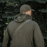 Mies metsässä M-Tac Tablet Bag Laser Cut Hex olkapäällä, päällään armeijanvihreä takki ja lippalakki.