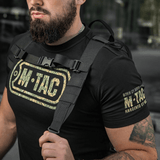Mies kantaa M-Tac STURM Elite -reppua taktisine hihnoineen ja M-Tac-logolla t-paidassa, sopii lyhyille retkille.