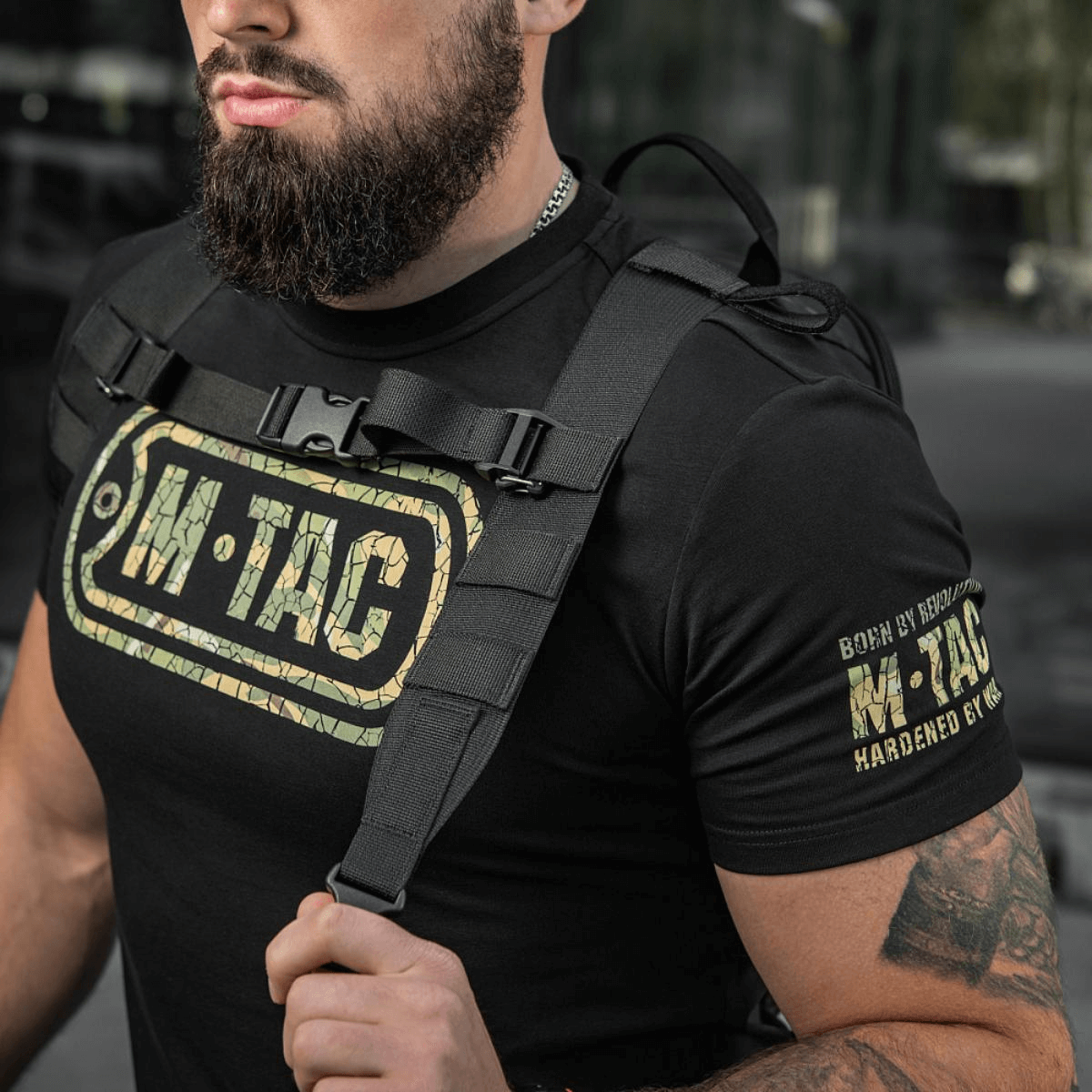 Mies kantaa M-Tac STURM Elite -reppua taktisine hihnoineen ja M-Tac-logolla t-paidassa, sopii lyhyille retkille.