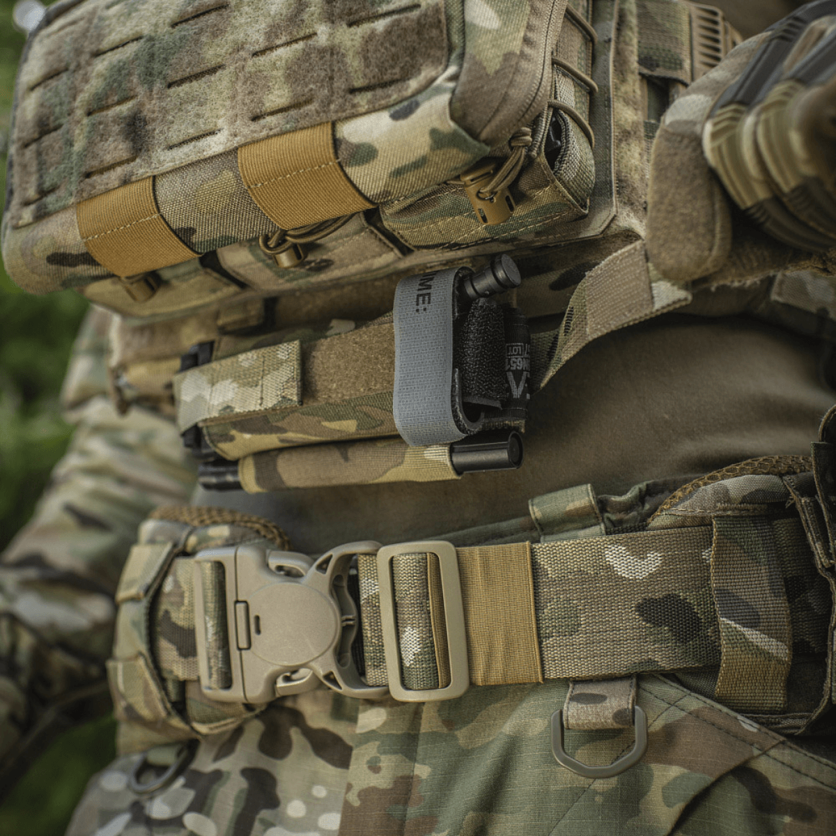 M‑Tac Tourniquet Pouch Elastic Gen.5 asennettuna taktiseen varustukseen, elastiset velcro-kiinnikkeet ja camo-kuvio.