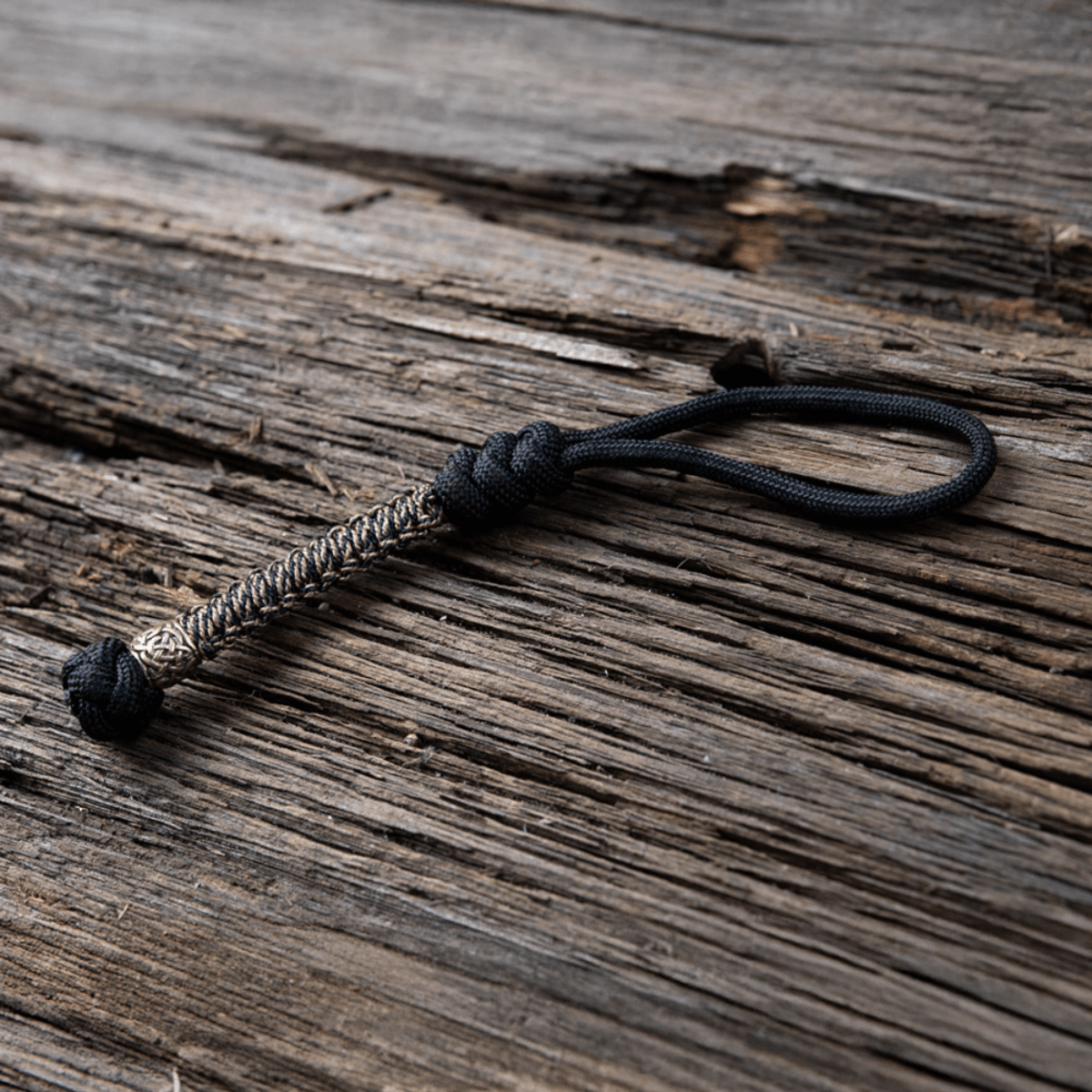 M-Tac Knife Lanyard Scandinavian punottu paracord, tyylikäs ja käytännöllinen lisä taskuveitsille, puutaustalla.