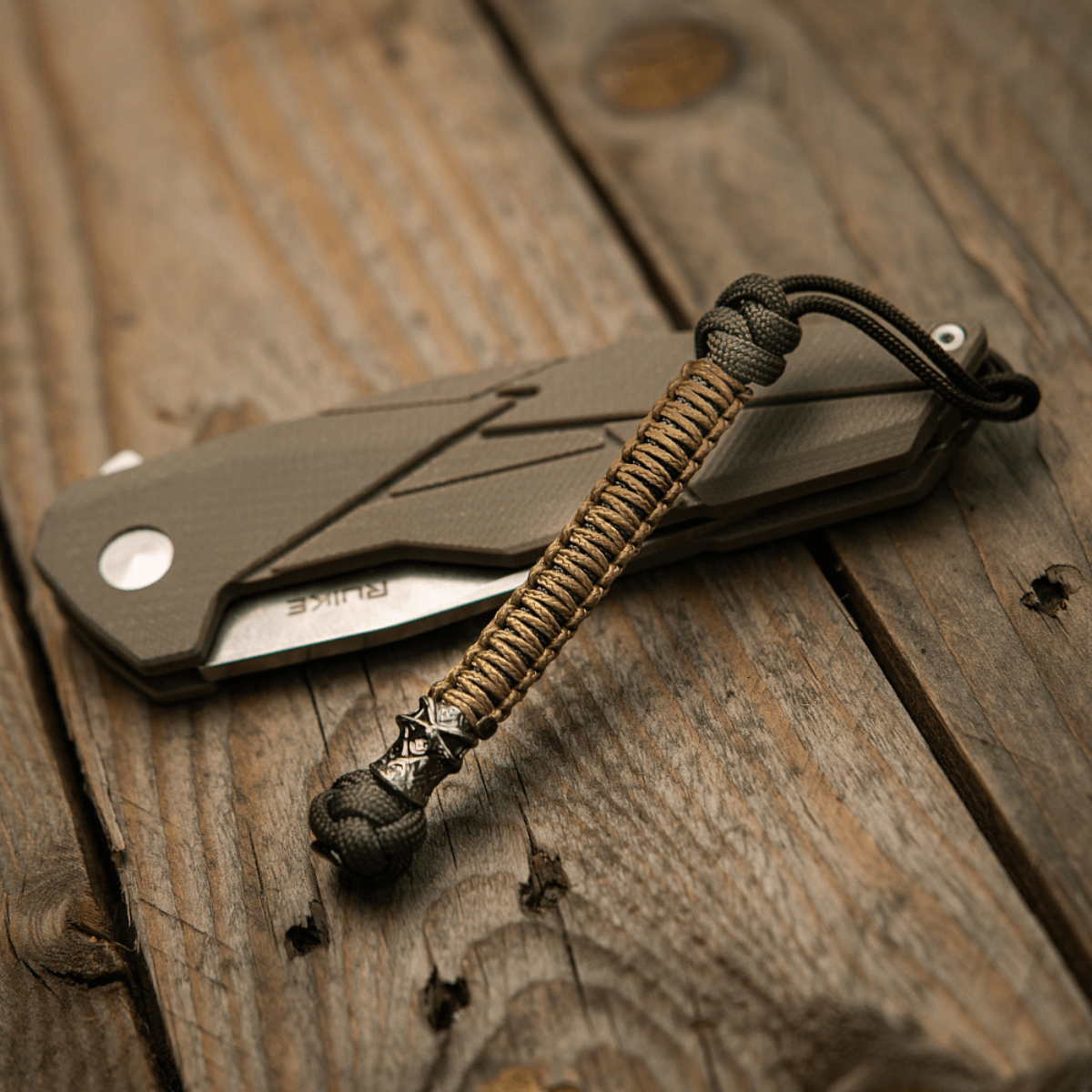 M-Tac Knife Lanyard Ninja paracord taittoveitsen vieressä puupöydällä