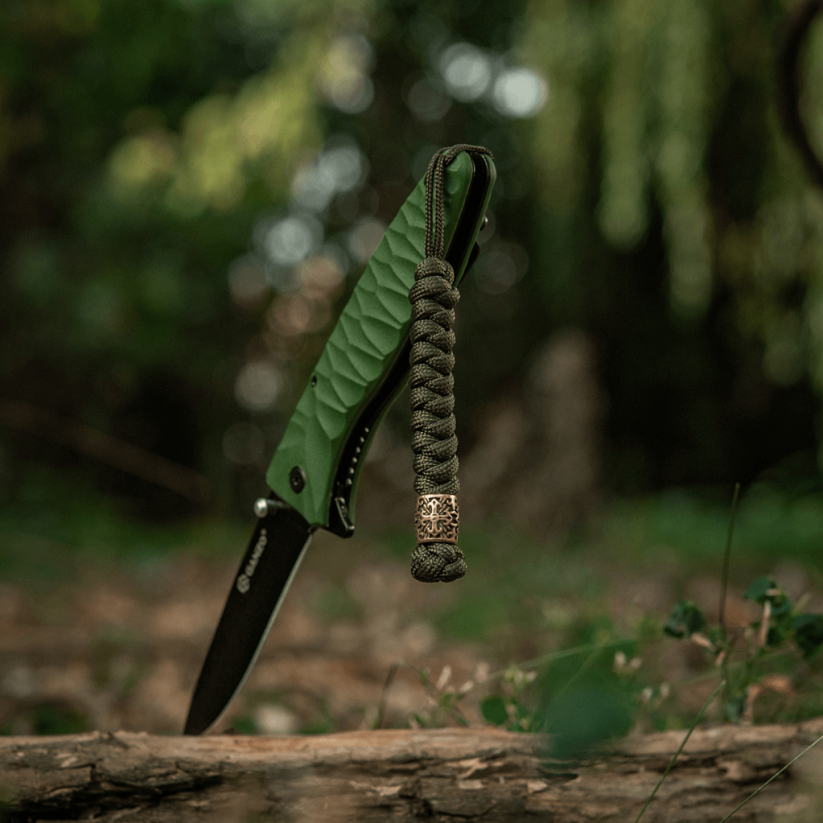 M-Tac Viper Lanyard Scandinavian punotulla paracordilla ja Viper-helmellä taskuveitsen vieressä luonnossa. Tyylikäs lisävaruste.