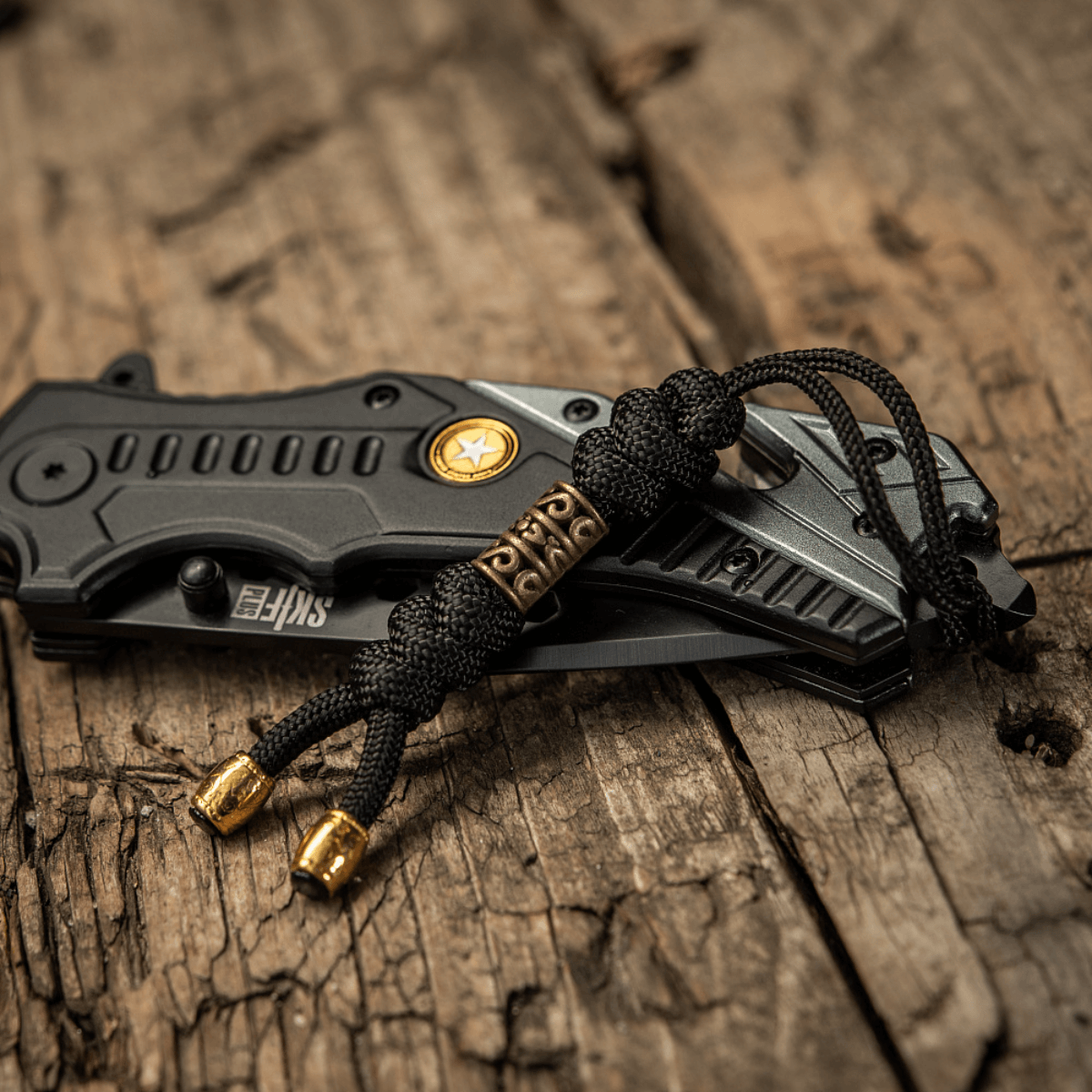 M-Tac Zeus Lanyard paracord taittoveitsen vieressä puupöydällä.