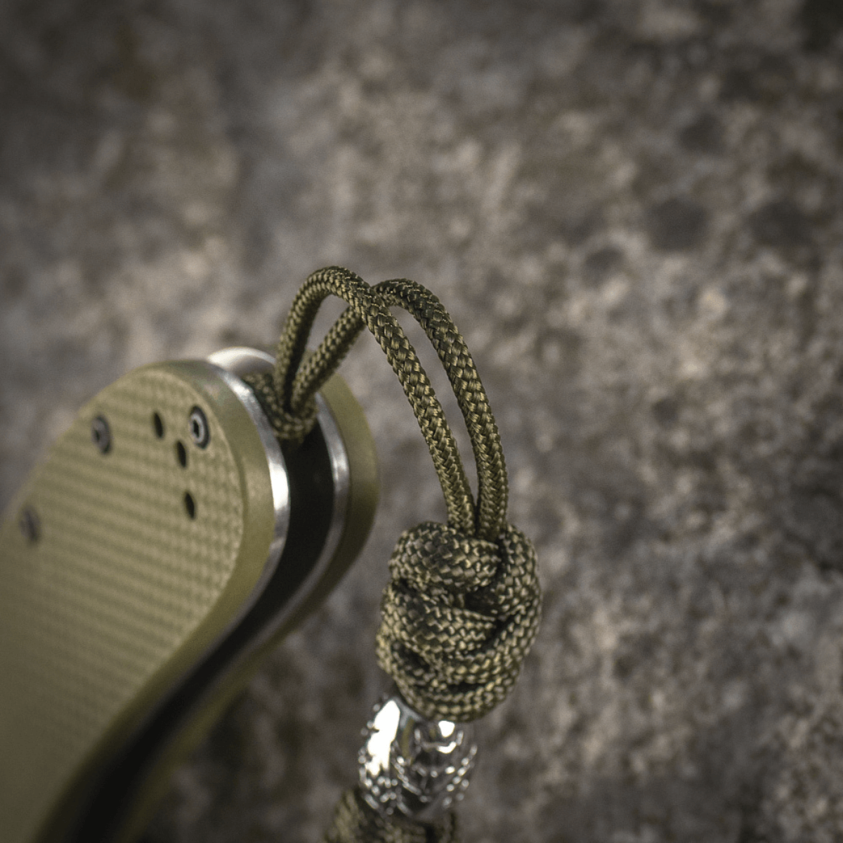 M-Tac Zeus Stainless Steel Lanyard, punottu paracord ja koristehelmi, kiinnitetty veitselle joustavaa pääsyä ja kestävyyttä varten.