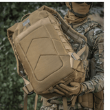 Sotilas M-Tac Large Assault Pack -repun kanssa urbaanissa maastokuviossa, näyttää MOLLE-kiinnityksen ja mukavat olkahihnat.