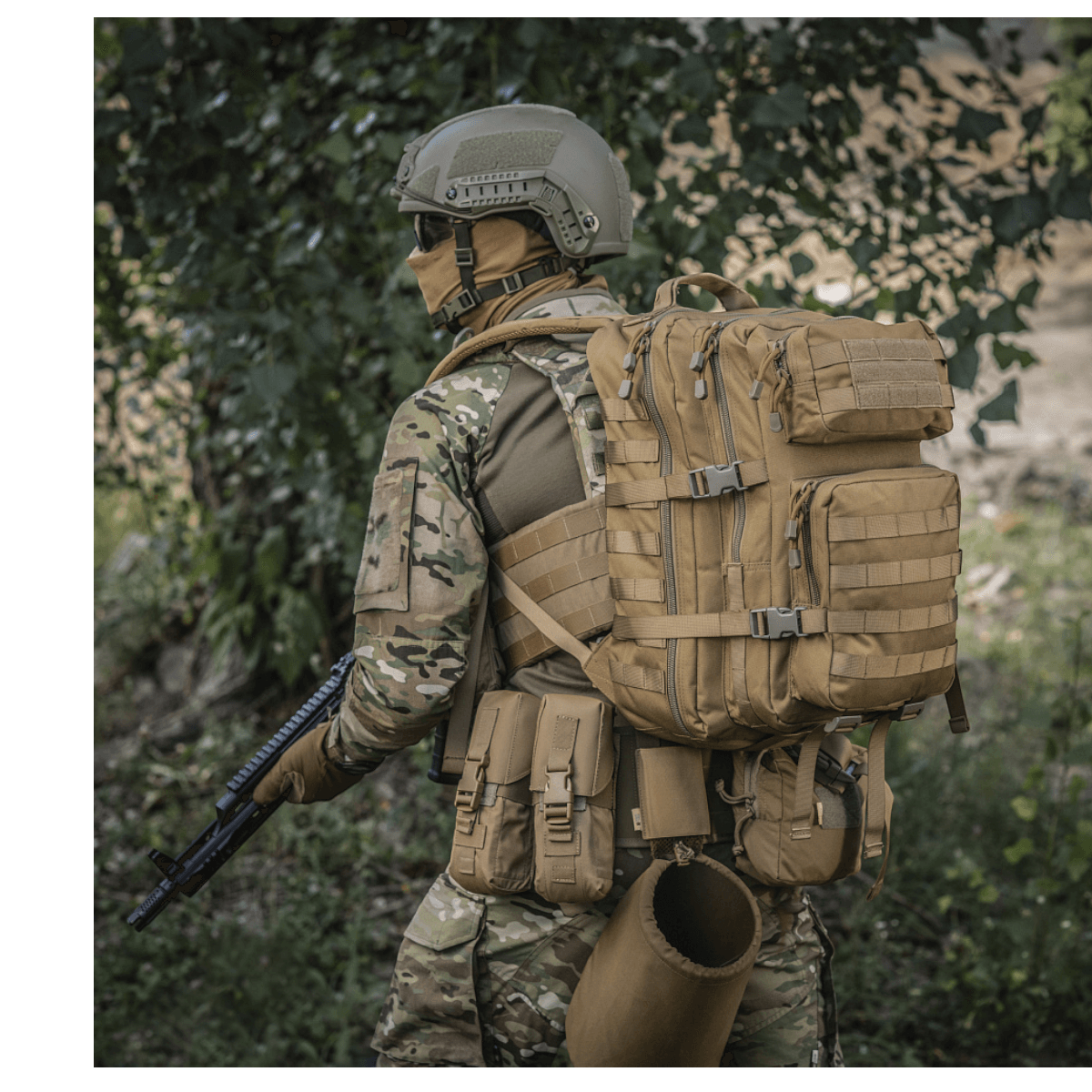M-Tac Large Assault Pack -reppu MOLLE-järjestelmällä, kantaja maastokuosisessa univormussa puiden alla.