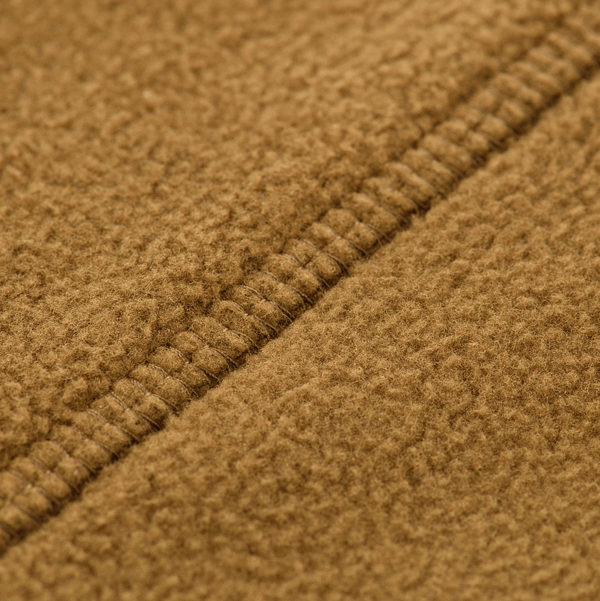 Lähikuva materiaalista M-Tac Lite Microfleece Hættetrøje -tuotteessa ompeleineen, näyttää kevyen ja joustavan mikrofleece-textuurin.